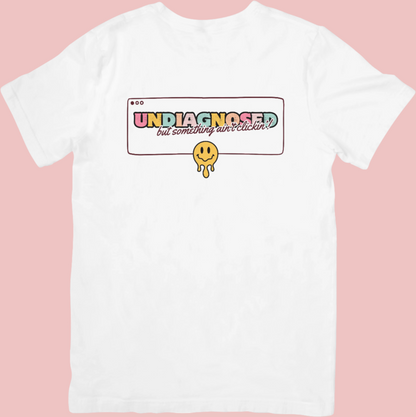Retro-style crew neck t-shirt with a smiley face design and the phrase ‘Undiagnosed: But The Math Ain’t Mathin’,’ celebrating neurodivergence and embracing the journey.